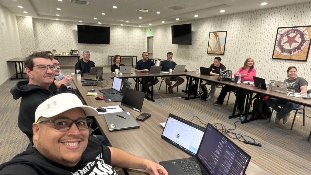 Jose Ponce Jr. with workshop attendees seated around tables with laptops.