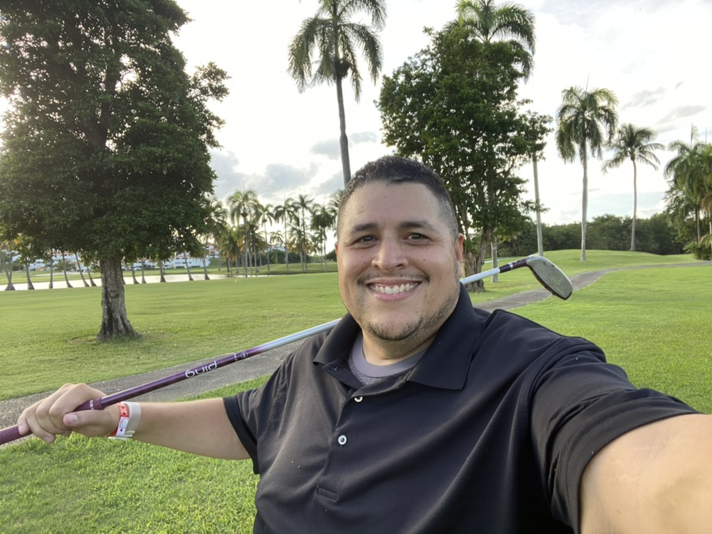 Jose Ponce Jr. smiling on a golf course.