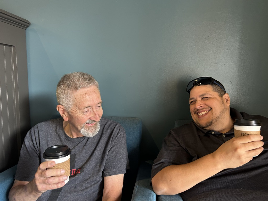 Jose Ponce Jr. and Richard Rose sharing coffee and laughing together.